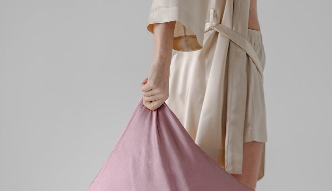 pale mauve color silk pillowcase in hand of a woman in silk robe